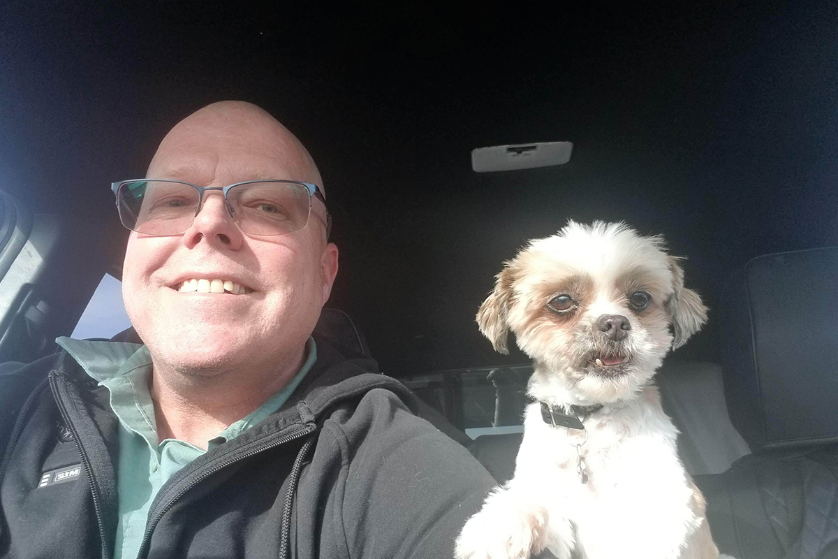 Smiling man with glasses and a small dog sitting in a vehicle, My Guy Plumbing Bozeman MT